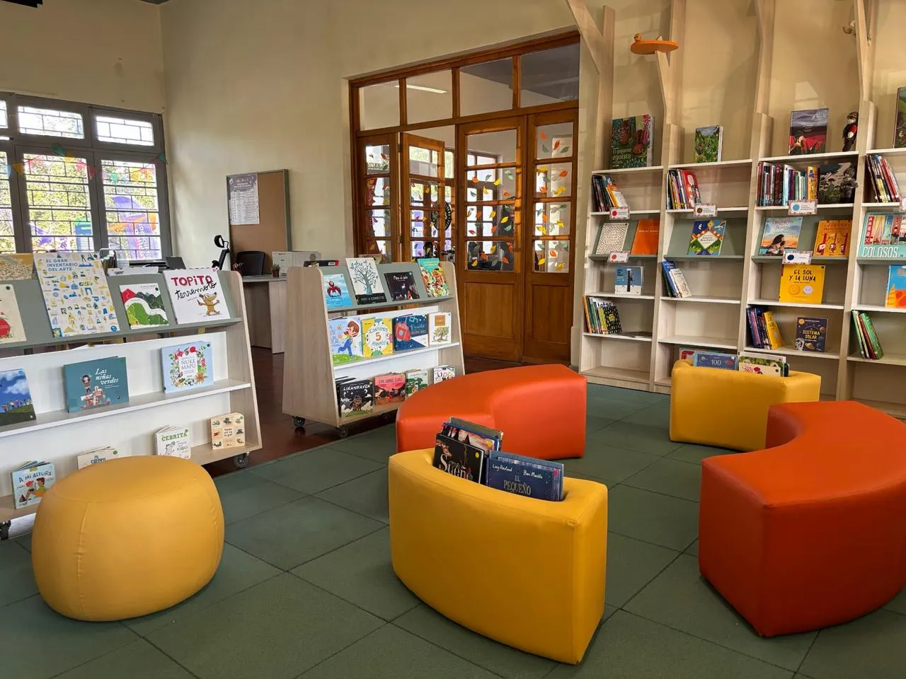 Sala de la Biblioteca Pública Infantil, con estantes de libros ilustrados y pufs de colores