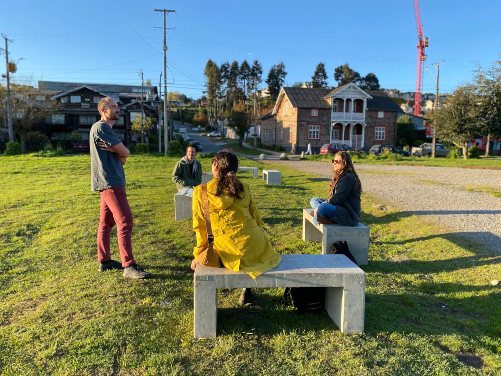 Personas conversando en bancas de hormigón sobre el pasto del parque
