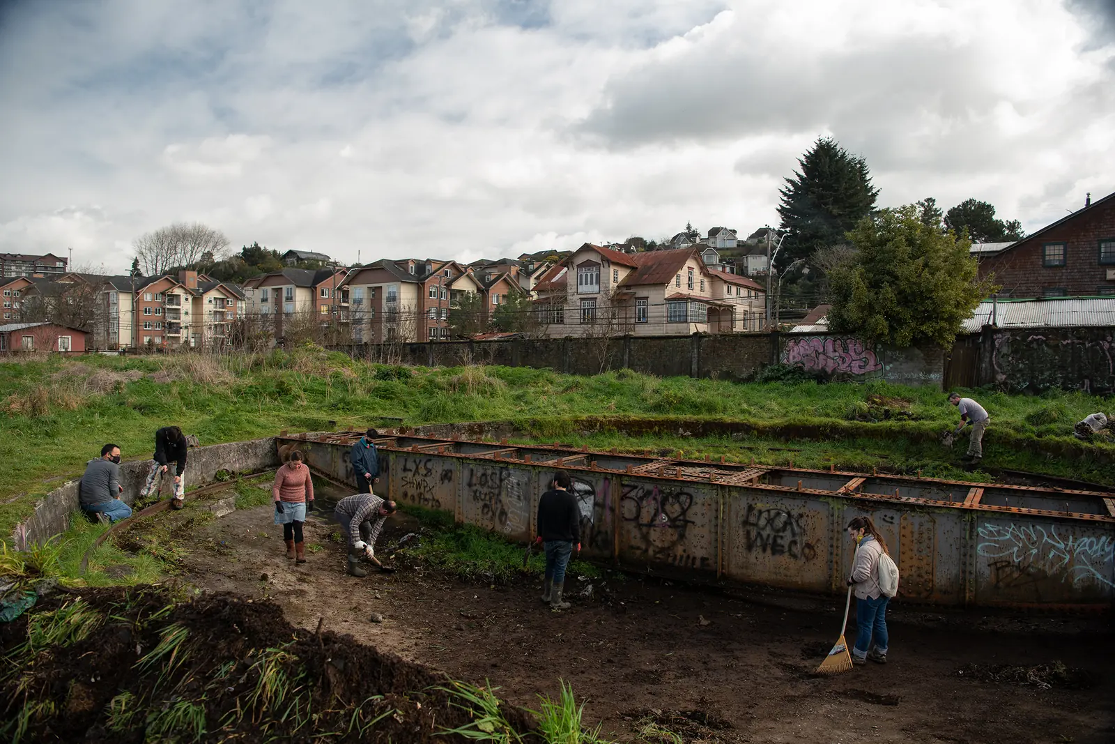 Vecinos con palas, rastrillos y guantes limpian la tornamesa histórica durante una jornada de voluntariado
