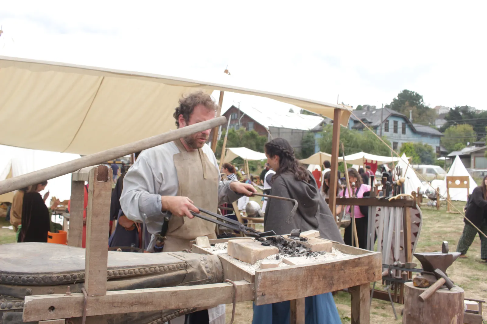 Herrero forjando con tenazas en un taller bajo toldo, en Feudo Medieval