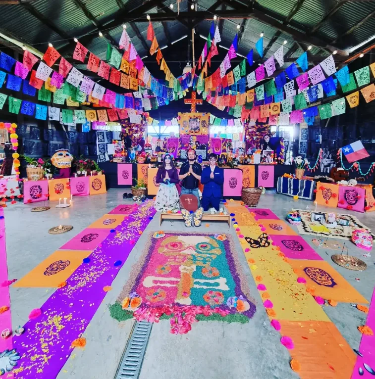 Altar de muertos en el Galpón Estación, con alfombra de aserrín de colores y papel picado