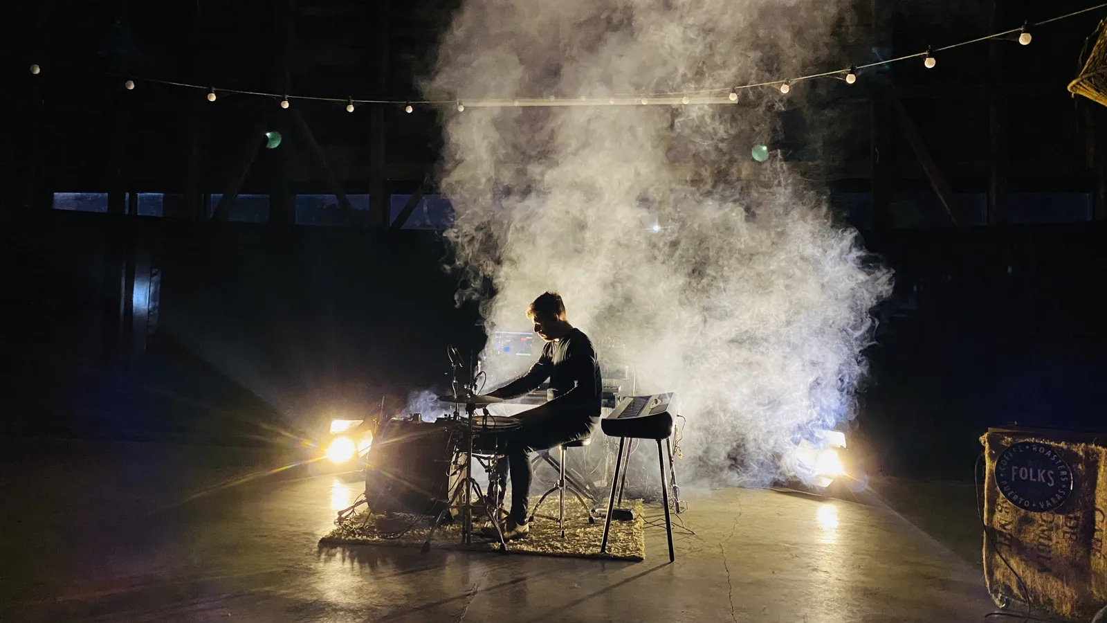 Músico tocando entre humo y luces en el galpón
