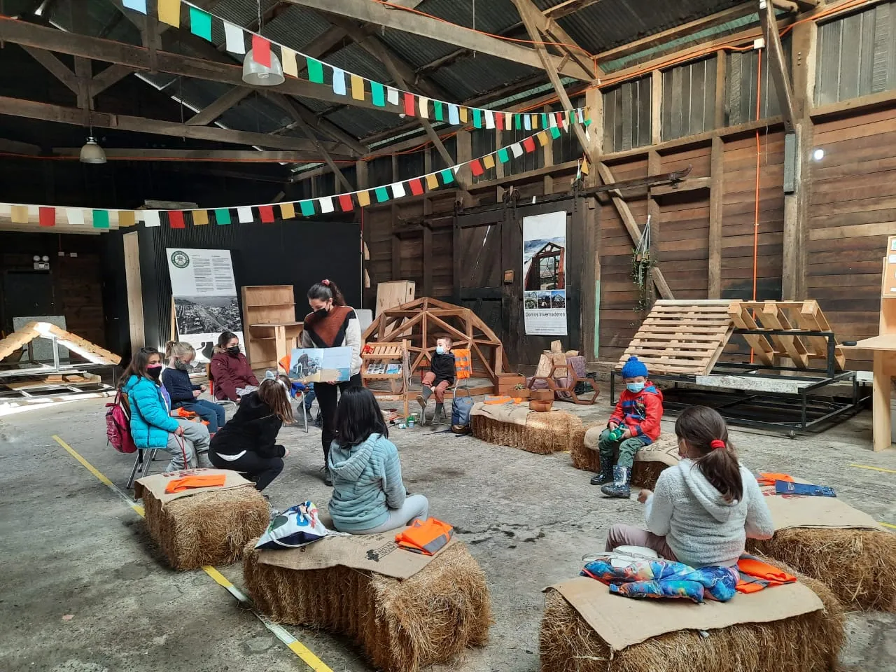 Niñas y niños sentados en fardos durante un taller en el Galpón Estación