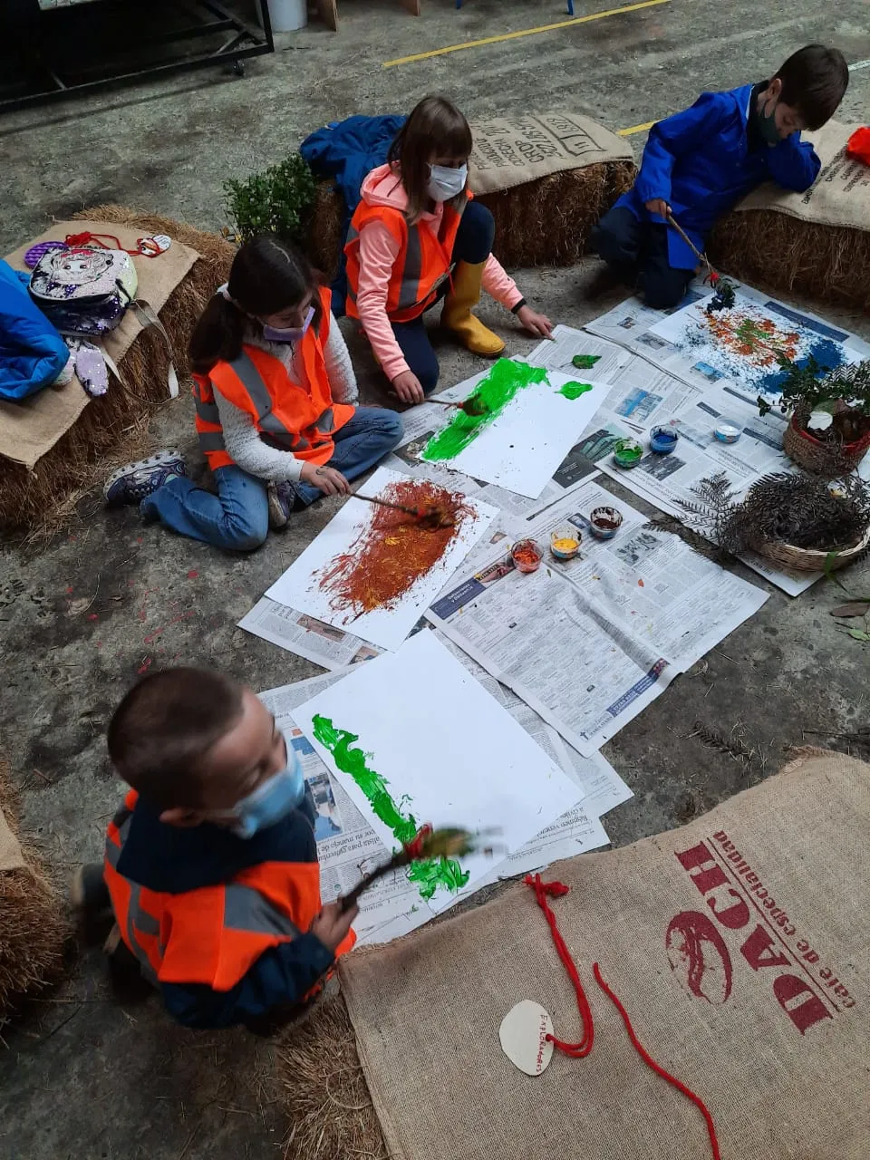 Niños pintando sobre papel en el suelo del galpón