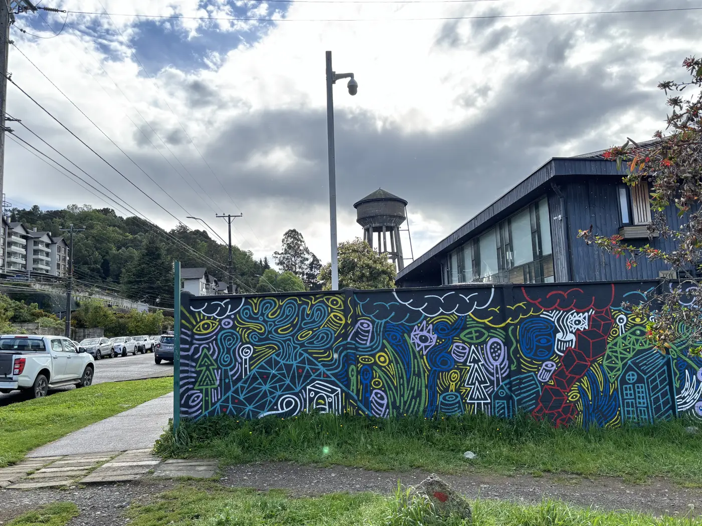 Muro pintado con murales de colores junto a la estación, con el estanque de agua al fondo
