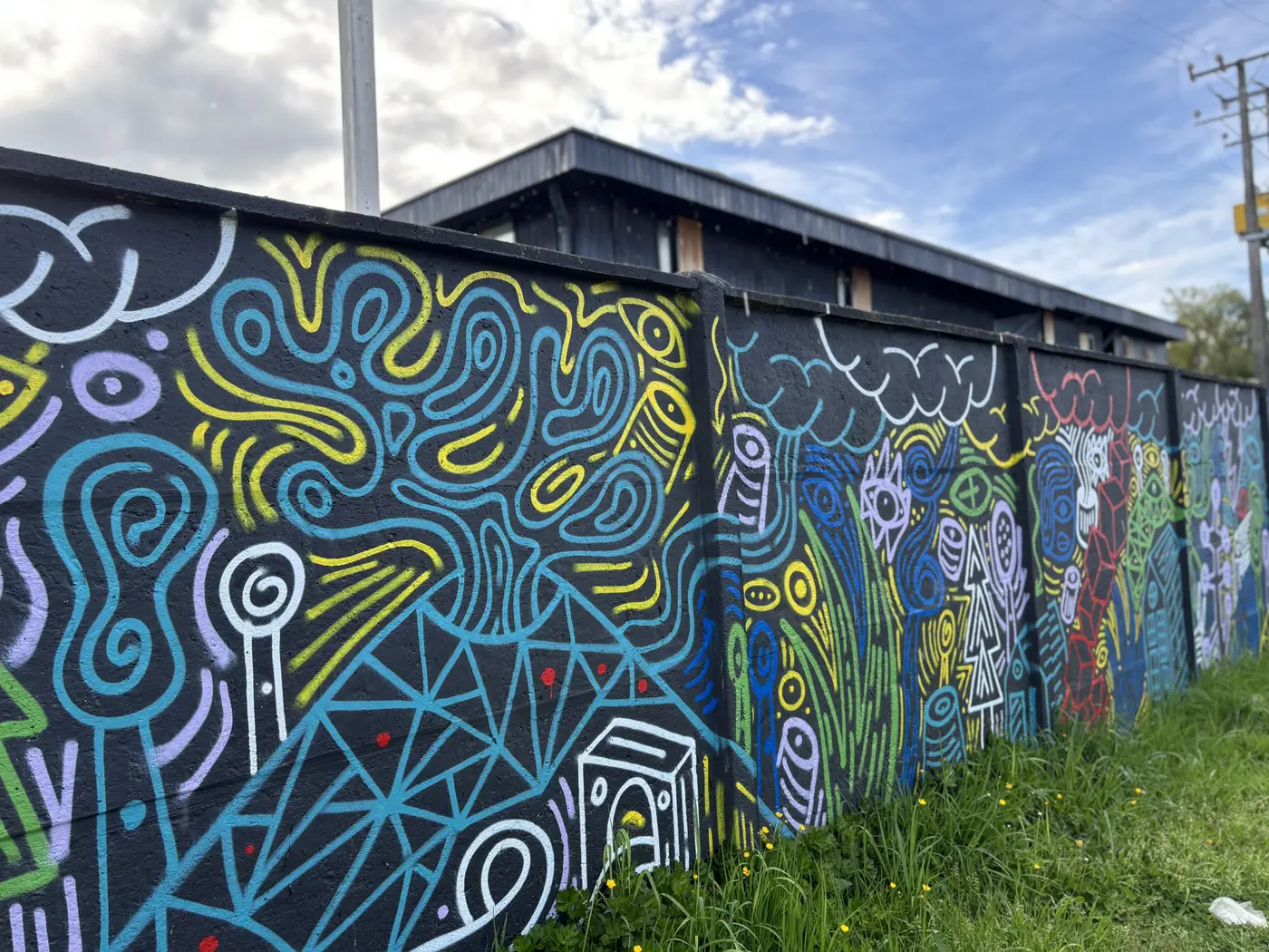 Detalle de los murales del muro: líneas, espirales y figuras en azul, amarillo y blanco