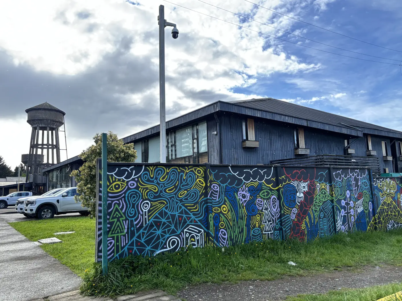 Muro con murales junto a la estación, con el estanque de agua ferroviario detrás