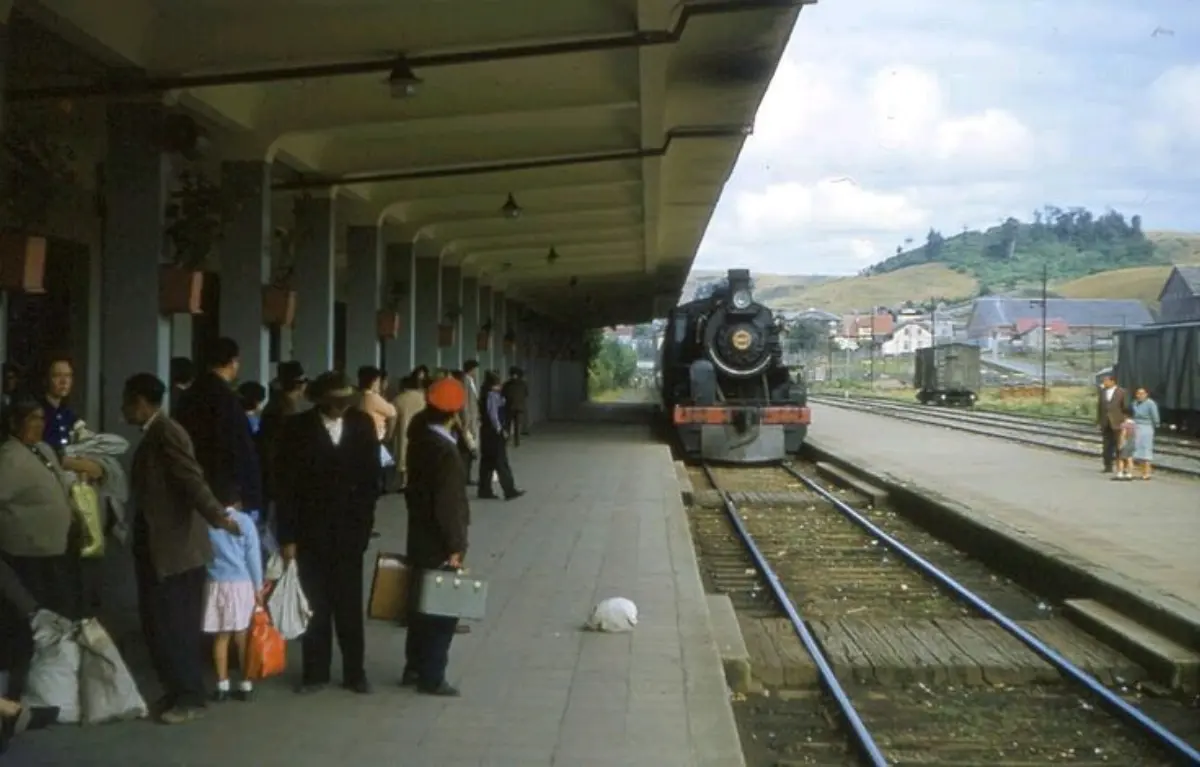 Fotografía histórica del andén de la estación de Puerto Varas, con pasajeros y una locomotora a vapor